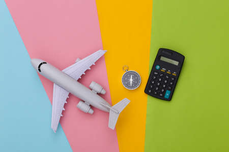 Compass, calculator and air plane on colored background. Cost of travel. top view