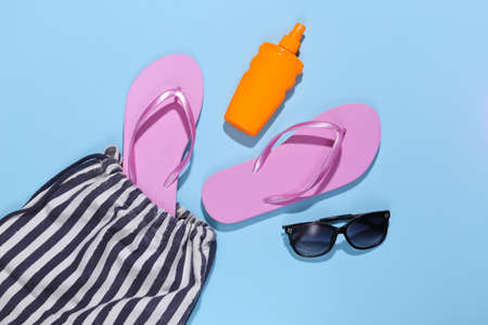 beach striped bag with accessories on blue background. Beach vacation concept. top view
