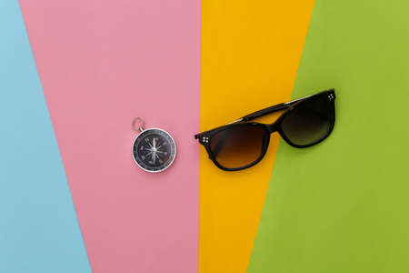 Compass and sunglasses on colored background. Travel, adventure flat lay. top viewの写真素材