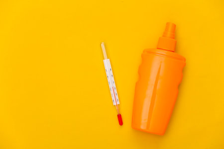 beach holidays. Sunblock bottle and thermometer on a yellow background. summer heat. top view. flat layの写真素材