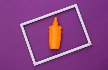 Sunblock bottle on purple background with white frame. skin protection. beach holidays. top viewの写真素材