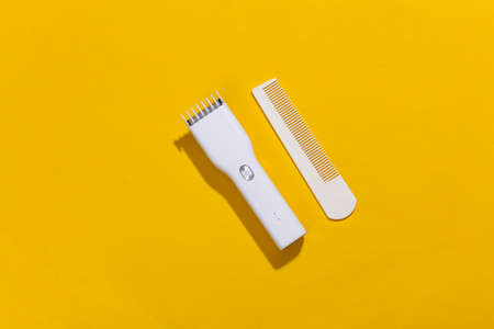 Wireless hair clipper and comb on yellow bright background. top viewの写真素材