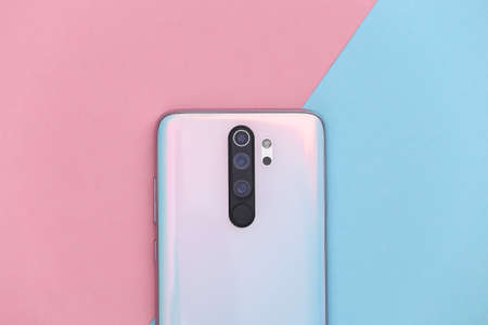 Modern smartphone back with lenses on a blue pink background. top viewの写真素材