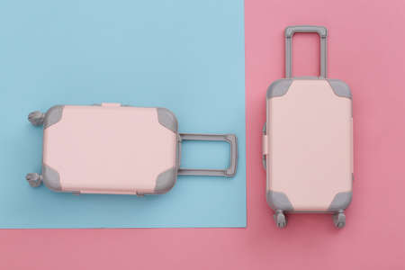 Two toy travel luggage on pink blue pastel background. travel planning. top view. flat layの写真素材