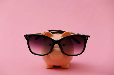 Piggy bank in sunglasses on a pink background