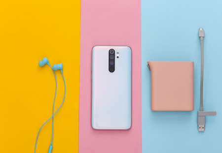 Modern gadgets. Smartphone, earphones and power bank on colored pastel background. top view
