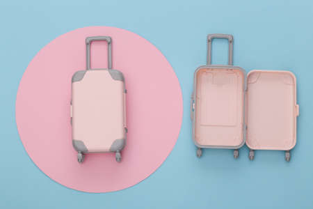 travel planning. Two toy travel luggage on blue background with pink circle. top view. flat layの写真素材
