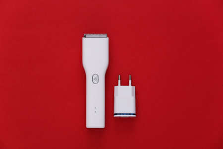 Wireless hair clipper with charger on red background. top viewの写真素材