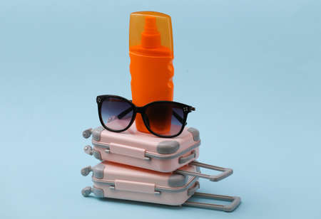 Travel, summer vacation or tourism concept. Two mini travel luggage suitcase with sunglasses and...