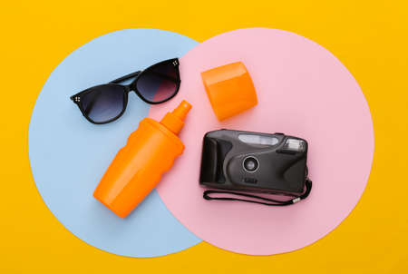 Sunblock bottle, sunglasses and camera on colored background. top viewの写真素材