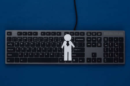 PC keyboard and paper businessman figurine on a classic blue background. top viewの写真素材