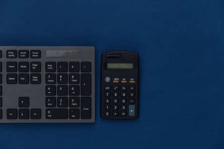 PC keyboard with calculator on a classic blue background. top viewの写真素材