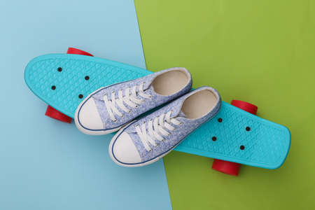 Cruiser board with sneakers on green blue background. youth entertainment. hipster outfit. top view....