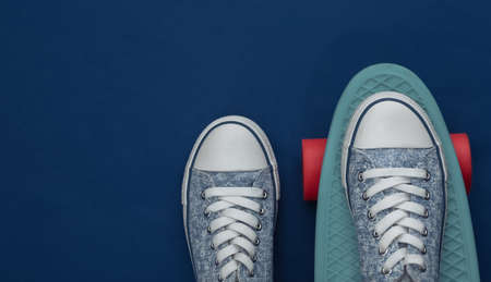 Cruiser board with sneakers on a classic blue background. youth entertainment. top view. flat layの写真素材