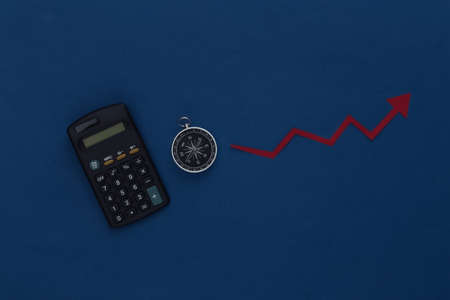 Calculator and compass with growth arrow tending up on a classic blue background. Trading, business and financial forecast concept.の写真素材