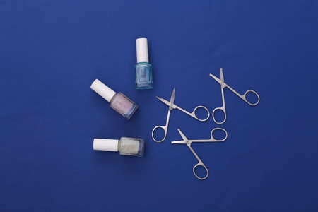Manicure scissors, nail polish bottle and clippers on classic blue background. beauty concept. nail care. top viewの写真素材