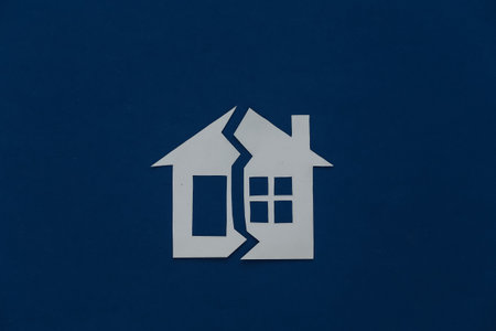 The concept of separation of property, divorce. Paper house cut in half on a classic blue backgroundの写真素材