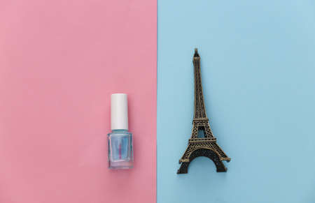 Nail polish and statuette of Eiffel tower on pink blue background. beauty concept. top viewの写真素材