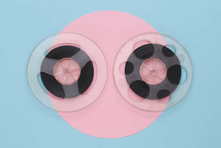 Audio magnetic tape. Two film reels on pink blue pastel background. top view. retro style. minimalism. 80sの写真素材