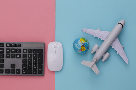 travel concept. PC keyboard and air plane, globe on pink blue background. top viewの写真素材