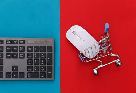 online supermarket. PC keyboard and shopping trolley on red blue background. top viewの写真素材