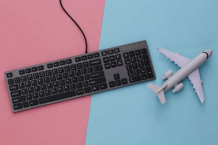 travel concept. PC keyboard and airplane on pink blue background. top viewの写真素材