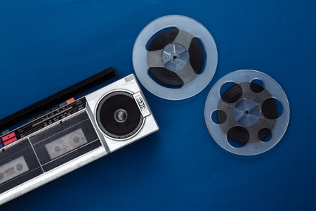 Retro flat lay. Retro portable stereo cassette recorder and audio magnetic tape reel on classic blue background. top view. 80sの写真素材