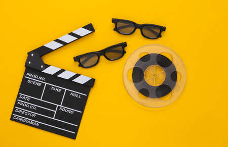 Movie clapper, film reel and 3D glasses on yellow background. entertainment industry. Cinema. top viewの写真素材