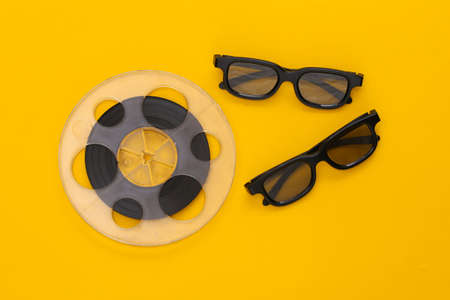 Film reel and 3D glasses on yellow background. entertainment industry. Cinema. top viewの写真素材