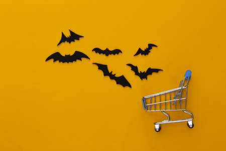 Halloween sale, shopping. Supermarket trolley and flying bats on blue background. Halloween decoration. top viewの写真素材