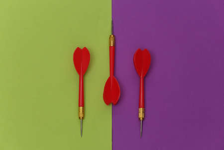 Three red plastic darts with metal tip on purple green background. top view. flat lay. minimalismの写真素材