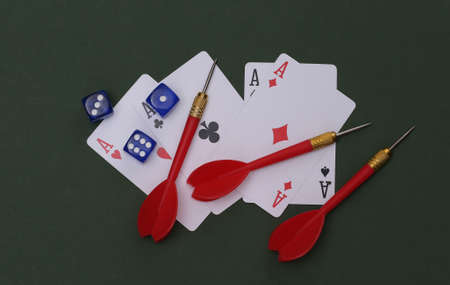 Gambling. Four aces, dice and darts on green background. top view. flat lay