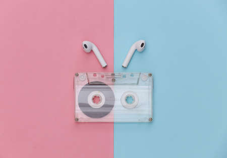 Retro audio cassette and wireless earphones on pink blue pastel background. top viewの写真素材