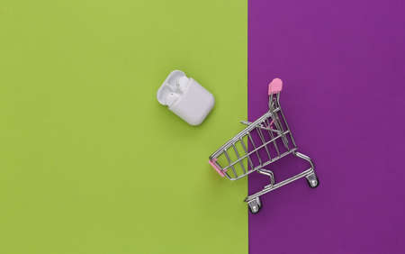 White wireless earphones with charging case on green purple background. top view. flat lay. minimalismの写真素材