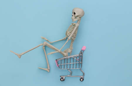 Shopping cart with skeleton on a blue background. top viewの写真素材