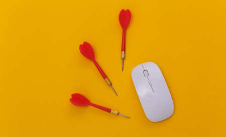 Pc mouse and darts on yellow background. top viewの写真素材