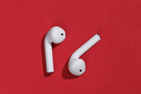 White true wireless bluetooth headphones or earbuds on bright red backgroundの写真素材