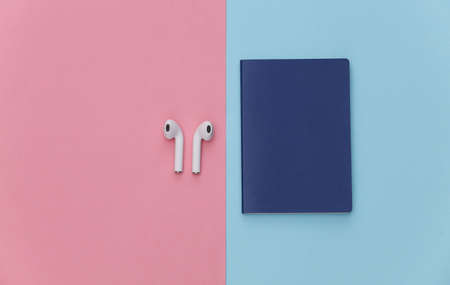 Passport and wireless earphones on a pink blue pastel background, travel concept. top viewの写真素材