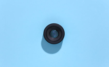 Camera lens on blue bright background with deep shadow. top view. flat lay. minimalismの写真素材