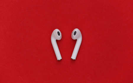 Modern wireless earphones on red background. top view. flat lay