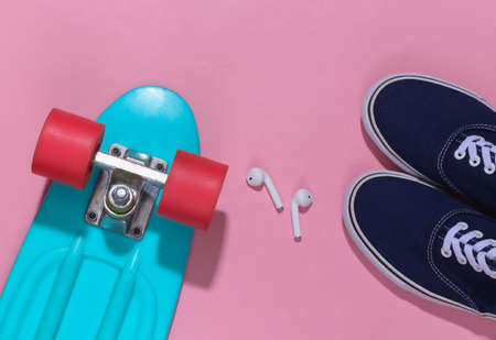 Cruiser board and wireless headphones, sneakers on a bright pink background. Youth accessories, hipster outfit. top view. flat layの写真素材