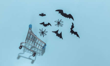Shopping cart with bats and spiders on a blue bright background. Halloween theme. top viewの写真素材