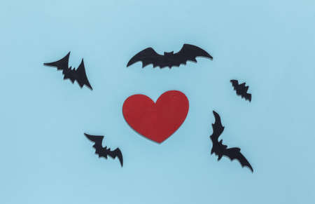 Red heart with bats and spiders on blue bright background. Halloween theme. top view