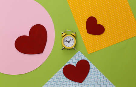 Hearts and alarm clock on creative colorful paper background. top view.の写真素材