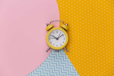 Yellow retro alarm clock on creative colorful paper background. top view. minimalismの写真素材