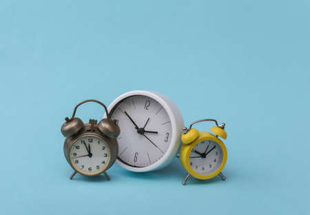 Many alarm clocks on blue background.