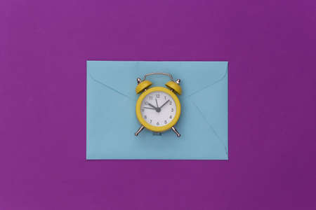 Mini alarm clock and envelopes on a purple background. top view. minimalismの写真素材