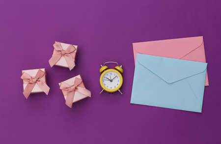 Mini alarm clock and gift boxes, envelopes on a purple background. top view. minimalismの写真素材