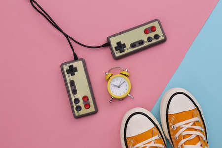 Youth retro sneakers, video cassette and mini alarm clock on pink blue pastel background. 80s. top view. flat layの写真素材
