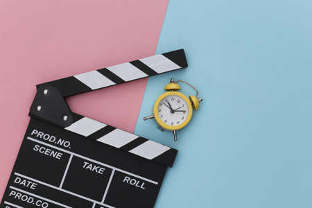 Movie clapperboard and mini alarm clock on a blue-pink pastel background. top viewの素材 [FY310181957874]